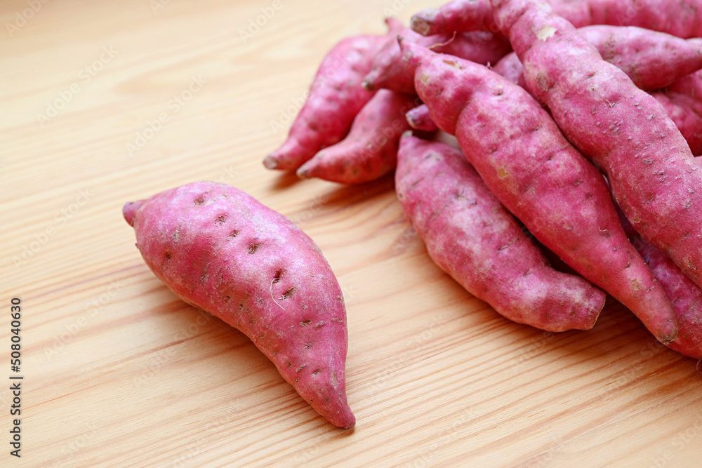 Closeup of Raw Purple Sweet Potatoes on Wooden Background Closeup of Raw Purple Sweet Potatoes on Wooden Background