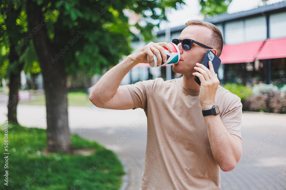 A bearded, smiling, stylish man in white shirt and sunglasses standing on the streets of the city and calling on mobile phone. A bearded, smiling, stylish man in white shirt and sunglasses standing on the streets of the city and calling on mobile phone.