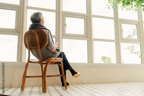 Lonely senior elderly man male enjoying looking out of window at home view from his window,Side view of a senior man who has a chronic illness Alzheimer's disease sitting in a living room