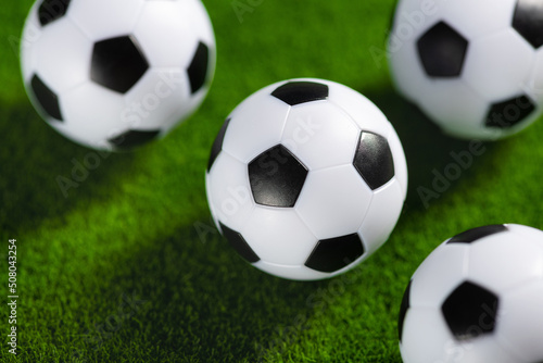 Several soccer balls on a green grass field. Start Qatar 2022.