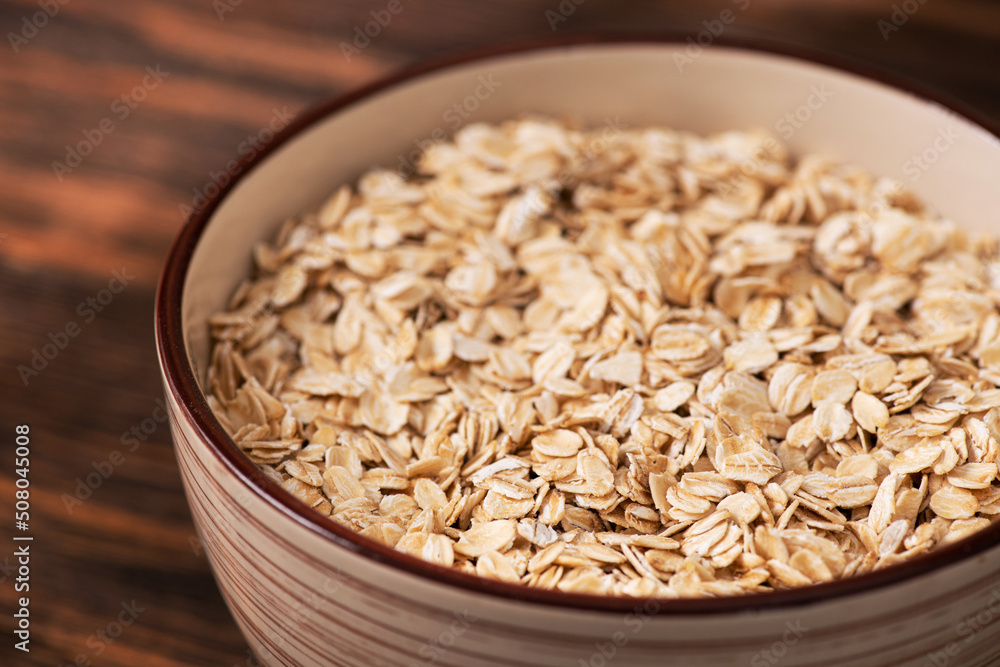 Bowl with oatmeal flakes on a wooden background Bowl with oatmeal flakes on a wooden background