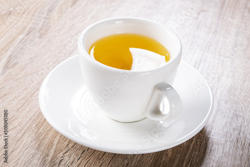 Hot yellow herbal tea in a white cup