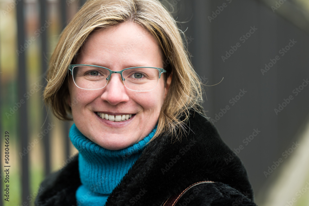 Portrait of a thirty year old white woman posing against an Industrial fence, wearing a black furry coat Portrait of a thirty year old white woman posing against an Industrial fence, wearing a black furry coat