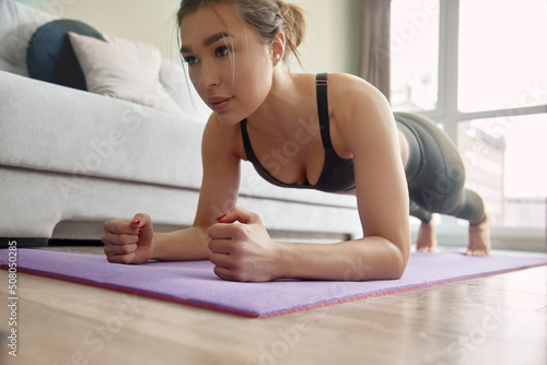 Girl training at home, woman doing plank