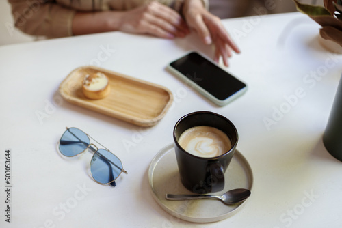 a cup of coffee  a smartphone and glasses on the table in a coffee shop. blog
