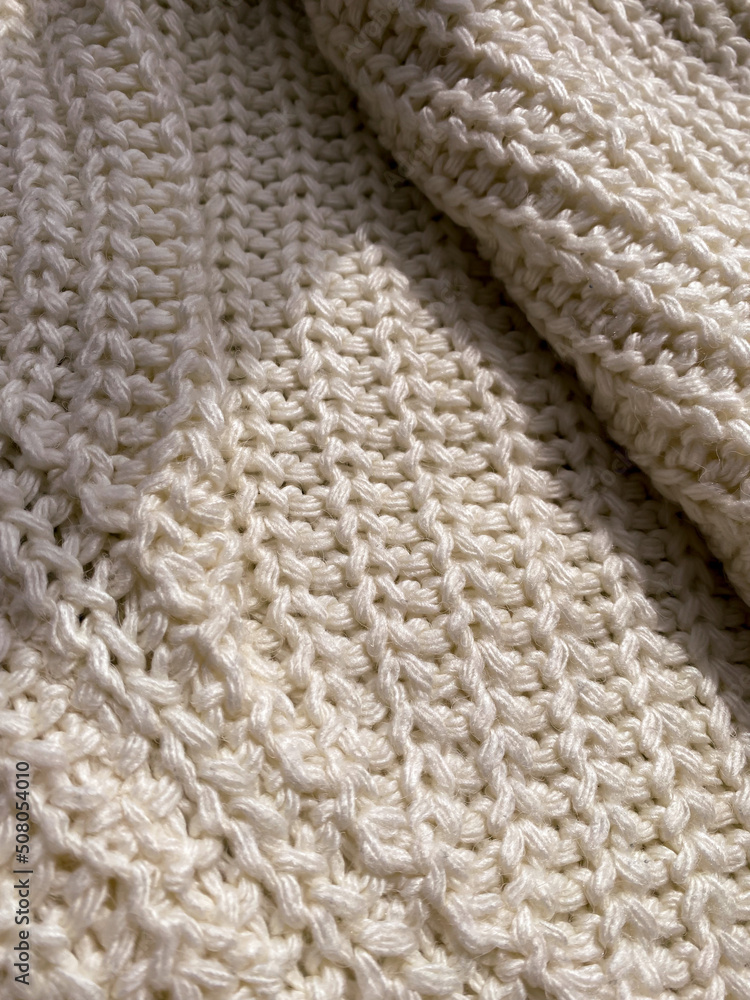 Knitted warm light sweater texture vertical photo with shadows. Cozy atmosphere, comfortable cloth, fabric for background design. Soft textile, close up Knitted warm light sweater texture vertical photo with shadows. Cozy atmosphere, comfortable cloth, fabric for background design. Soft textile, close up