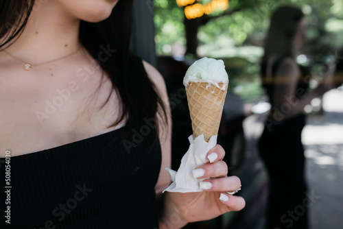Girl holding ice cream in her hands on a background of the body. Girl holding ice cream in her hands. Delicious ice cream in the summer. Summer and heat.