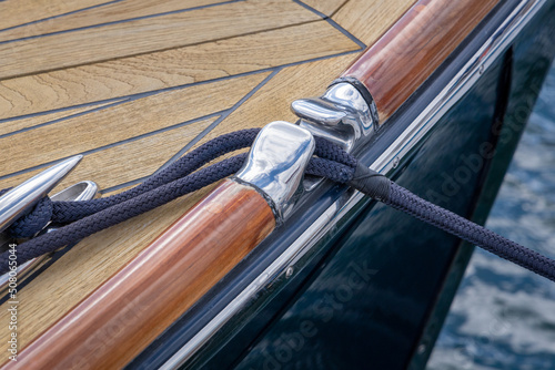 Navy Rope Running Through Chrome Fairlead Onto Teak Deck of Yacht