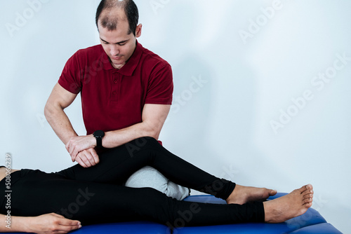 Boy therapist applying therapeutic acupressure on a young athletic woman