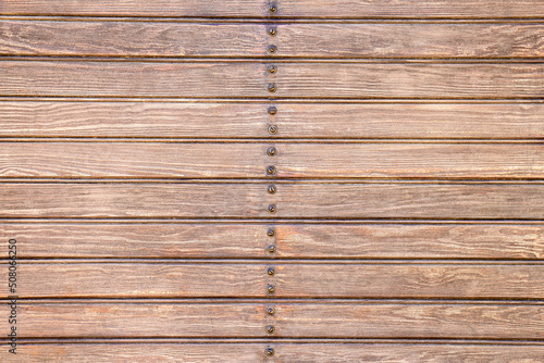Background of brown wooden slats with screws in the center.