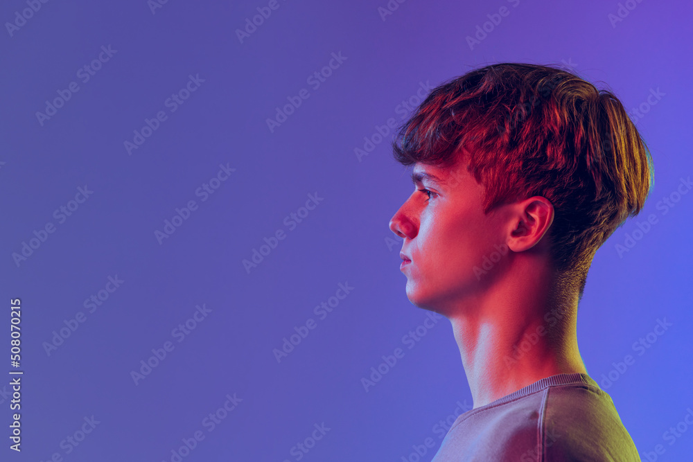 Profile view young red-headed man, student isolated over blue studio background in neon light. Concept of youth, fashion, emotions, facial expression Profile view young red-headed man, student isolated over blue studio background in neon light. Concept of youth, fashion, emotions, facial expression