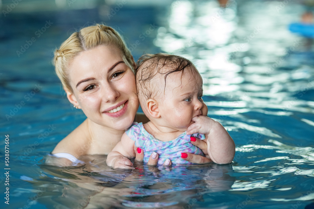 Young beautiful blonde mother with baby in pool. Concept of sport, training and family Young beautiful blonde mother with baby in pool. Concept of sport, training and family