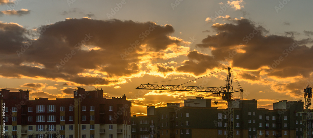 Sunset over the buildings and construction crane