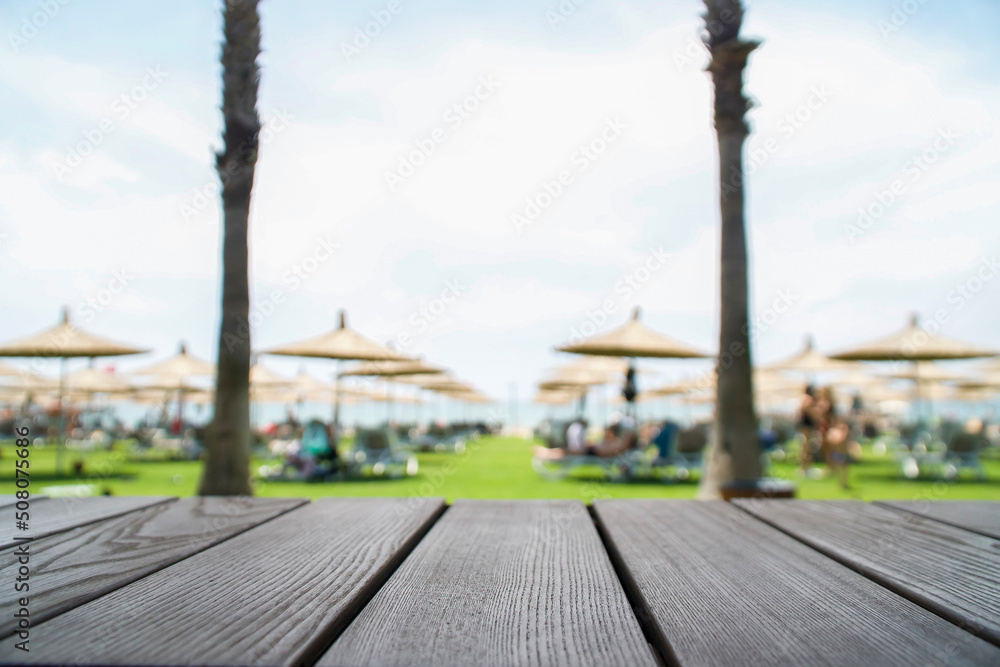 Wooden table in front with blurred background. Wooden desk, empty counter in front of beautiful beach resort 