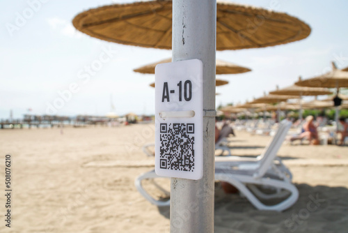 QR code on the pole on blurred beach. QR code with seat number A - 10 for select menu