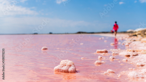 Vue des salins d'Aigues-mortes avec du sel en formation au premier plan, un enfant se promenant et les marais à l'arrière plan par une journée ensoleillée