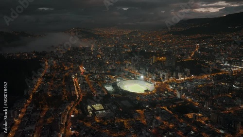 Nighttime drone shot over Quito shows lit up Atahualpa Olympic Stadium