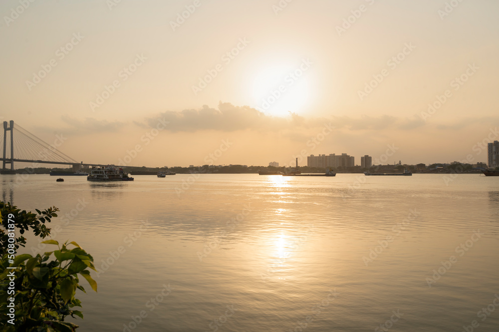 Sunray reflect on the Ganga River beside Hooghly Bridge. Princep Ghat at Kolkata. Beautiful sunset.