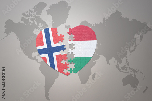 puzzle heart with the national flag of norway and hungary on a world map background. Concept.
