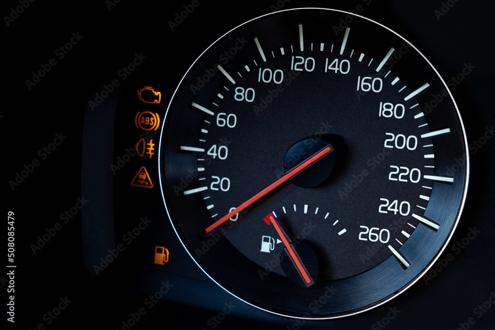 Close-up Instrument car panel with speedometer, low fuel level, ABS and other icons. Engine start and stop. Fuel crisis concept. High price for a diesel, gasoline, oil and natural resources. Red lit