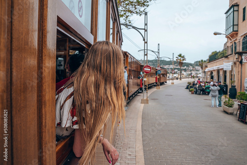 Mallorca, Spain. April 27, 2022. Woman traveling in vintage tram while sightseeing. Traditional train is moving by buildings. She is spending leisure time in public transport at old town. photo
