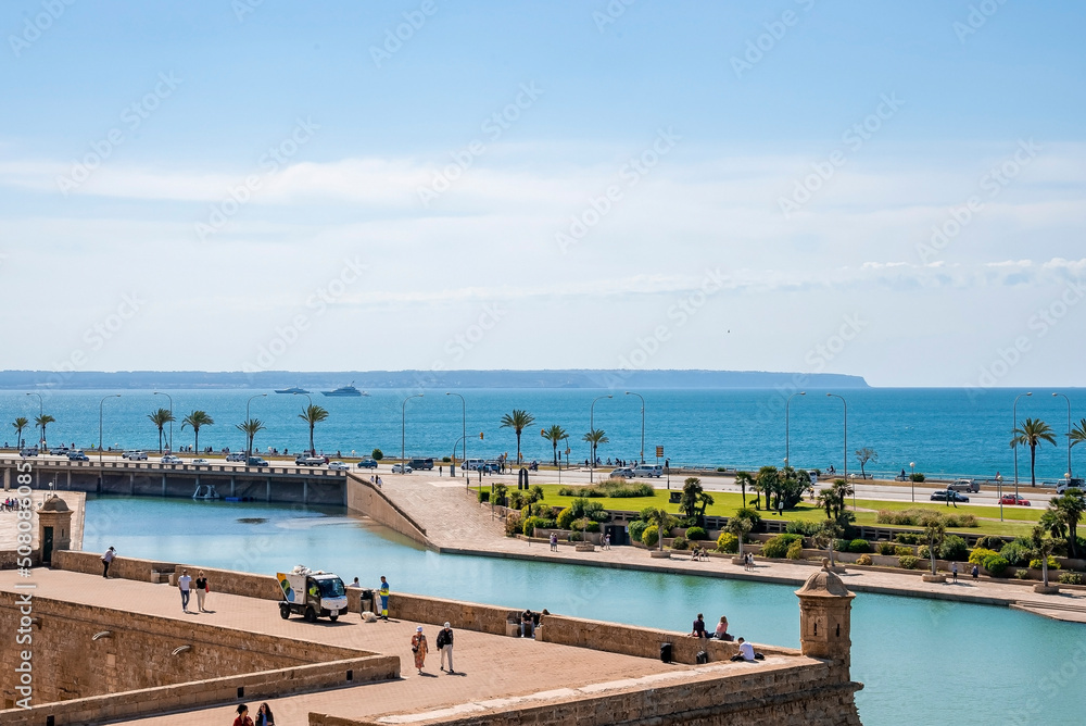 Mallorca, Spain. April 27, 2022. View of canal and seascape through church. Tourists exploring La Seu cathedral in city against blue sky. People enjoying vacation in summer.