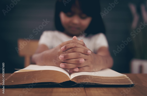 Little girl praying with bible in church
