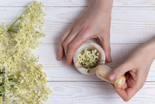 Mortar and pestle with elder flowers. Phytotherapy and herbal medicine concept.