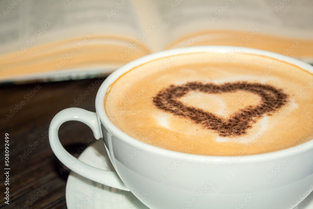 Fototapeta premium Coffee drink near the book. Coffee up close. Heart in coffee