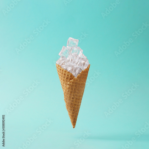 Creative layout made of Ice cream cone with ice cubes on blue background. Minimal summer concept.