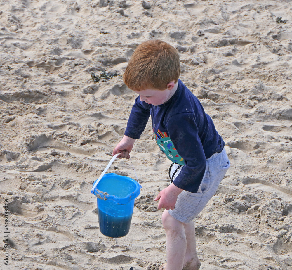 Red headed boy playing on a sandy beach in Northern Ireland Holidays UK Red headed boy playing on a sandy beach in Northern Ireland Holidays UK