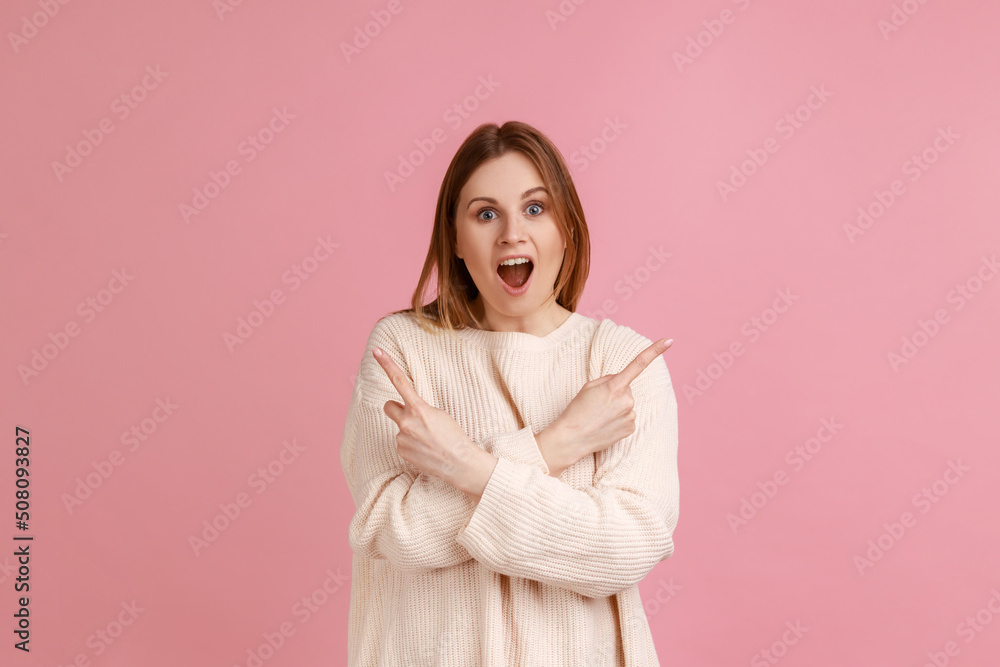 Portrait of beautiful amazed blond woman standing with crossed hands and pointing to copy space on both sides, wearing white sweater. Indoor studio shot isolated on pink background. Portrait of beautiful amazed blond woman standing with crossed hands and pointing to copy space on both sides, wearing white sweater. Indoor studio shot isolated on pink background.