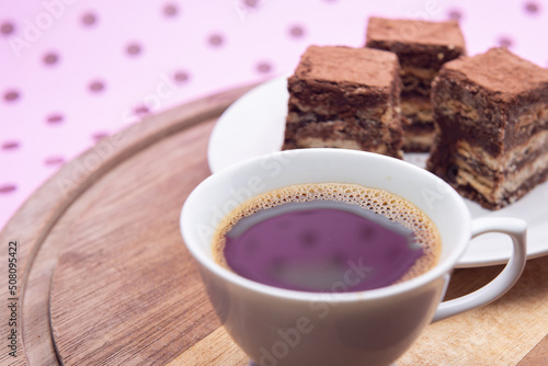 Uma xícara com café e palha italiana sobre madeira, sobre superfície cor-de-rosa. 