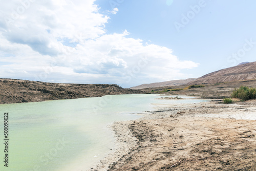 Sinkhole filled with turquoise water  near Dead Sea coastline. Hole formed when underground salt is dissolved by freshwater intrusion  due to continuing sea-level drop. . High quality photo