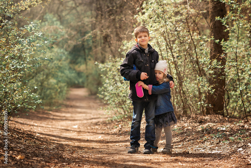 brother and sister are walking in the forest and hugging 