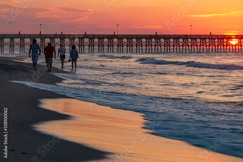 group of four people walking on the beach front in Myrtle Beach. South Carolina on a colorful early summer  morning. photo