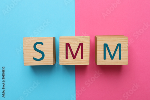 Abbreviation SMM made with wooden cubes on color background, flat lay. Social Media Marketing