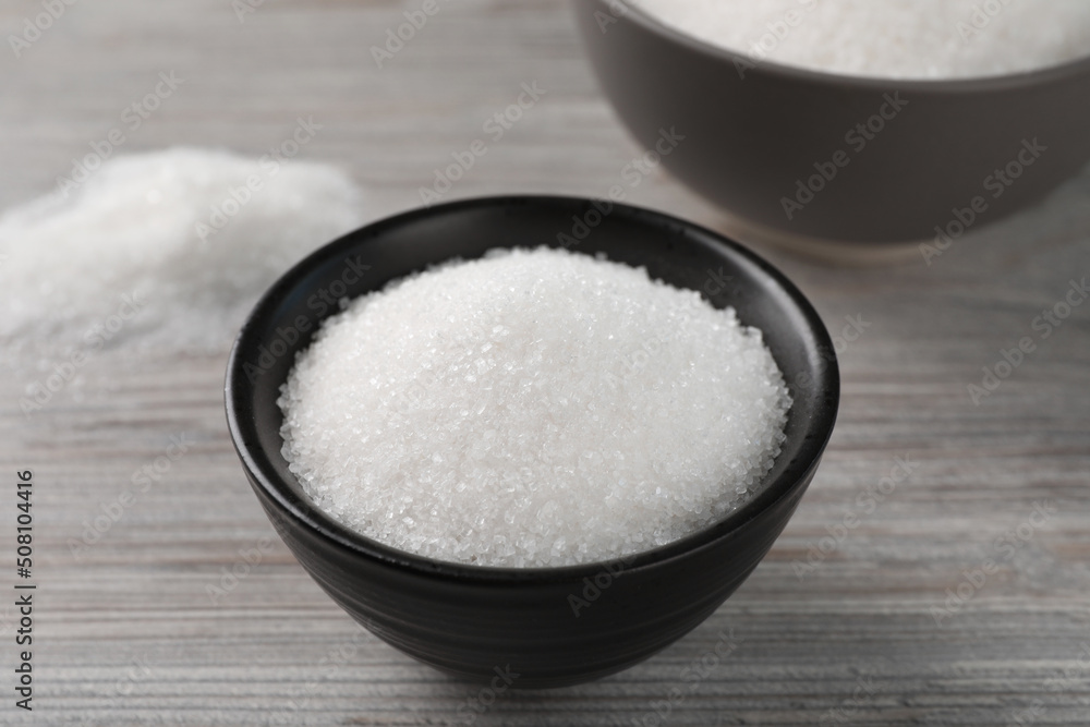 Granulated sugar on light wooden table, closeup Granulated sugar on light wooden table, closeup