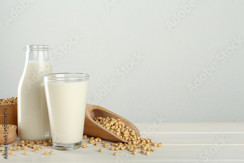 Fresh soy milk and grains on white wooden table. Space for text