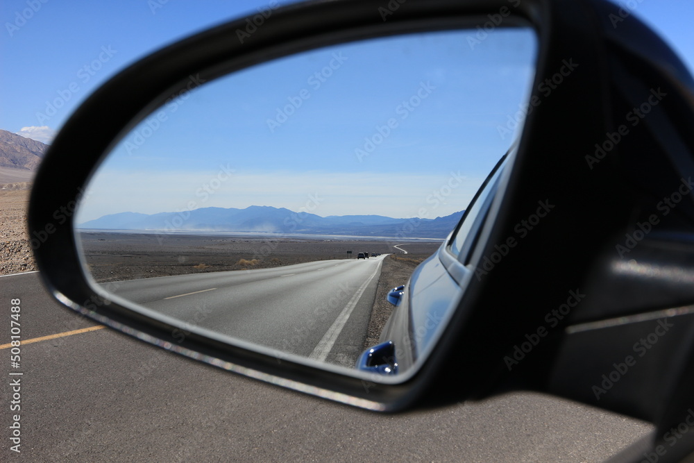 road in the desert valley of death view from the mirror of a car