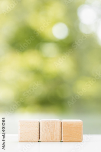 Business concept - Abstract geometric real floating wooden cube on green summer background