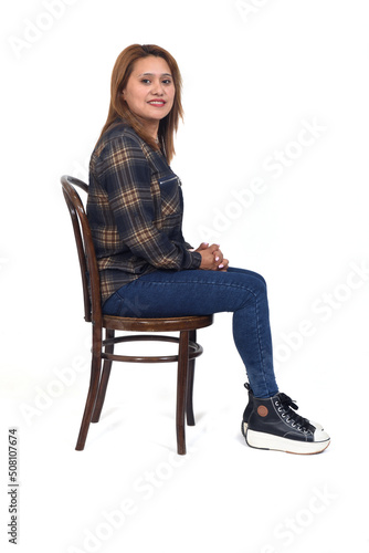 side view of a woman sitting on chair, looking at camera on white background