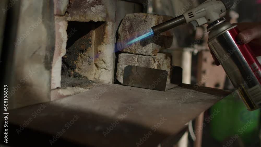 The blacksmith sets fire to the burner. Craftman metal worker rings fire to a forge furnace. The blacksmith sets fire to the burner. Craftman metal worker rings fire to a forge furnace.