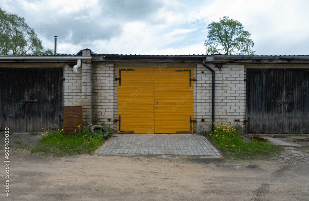 yellow wooden garage door between two unpainted