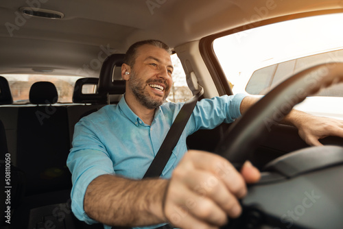 Obraz na plátne Happy man in earphones enjoying music driving luxury car