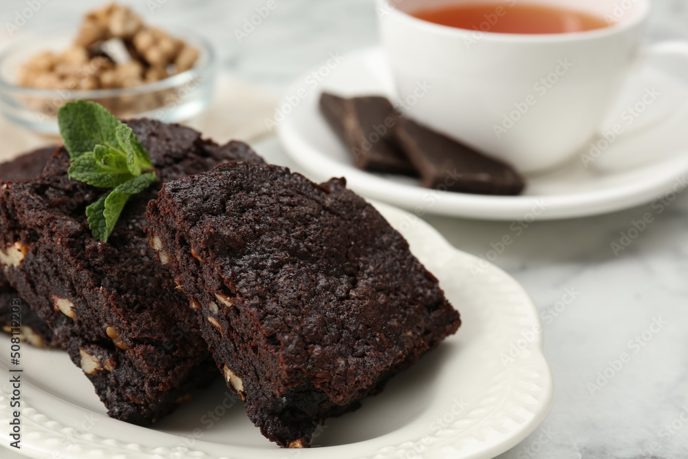 Delicious brownies with nuts and mint on white table, closeup. Space for text Delicious brownies with nuts and mint on white table, closeup. Space for text