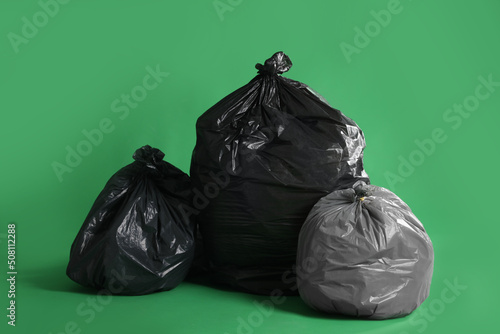 Trash bags full of garbage on green background