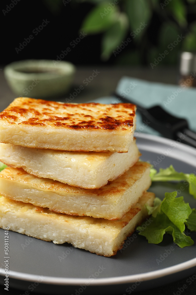 Delicious turnip cake with lettuce salad served on grey plate, closeup