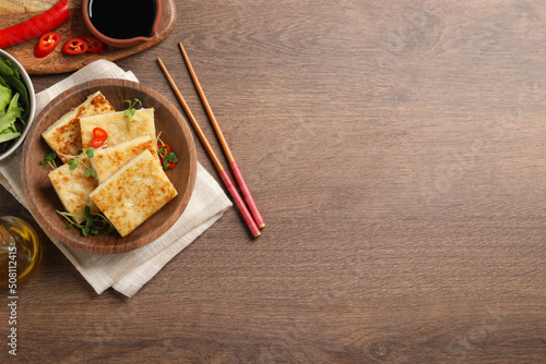 Delicious turnip cake with microgreens served on wooden table, flat lay. Space for text photo