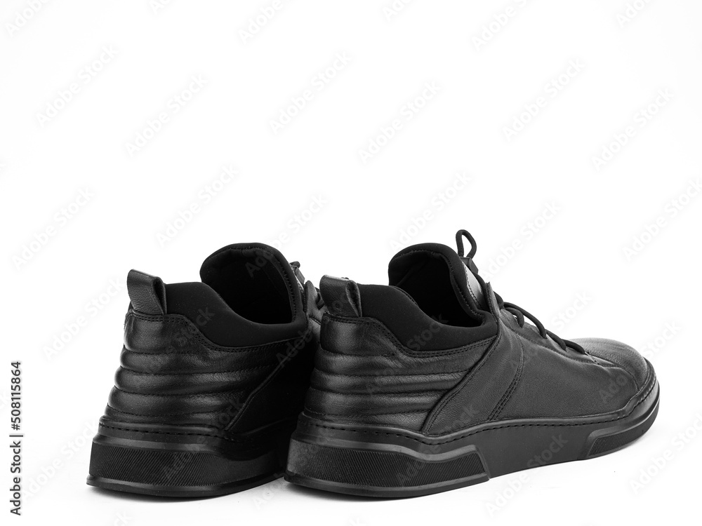 Black leather classic sneakers with laces. Casual men's style. Black rubber soles. Isolated close-up on white background. Back side view.